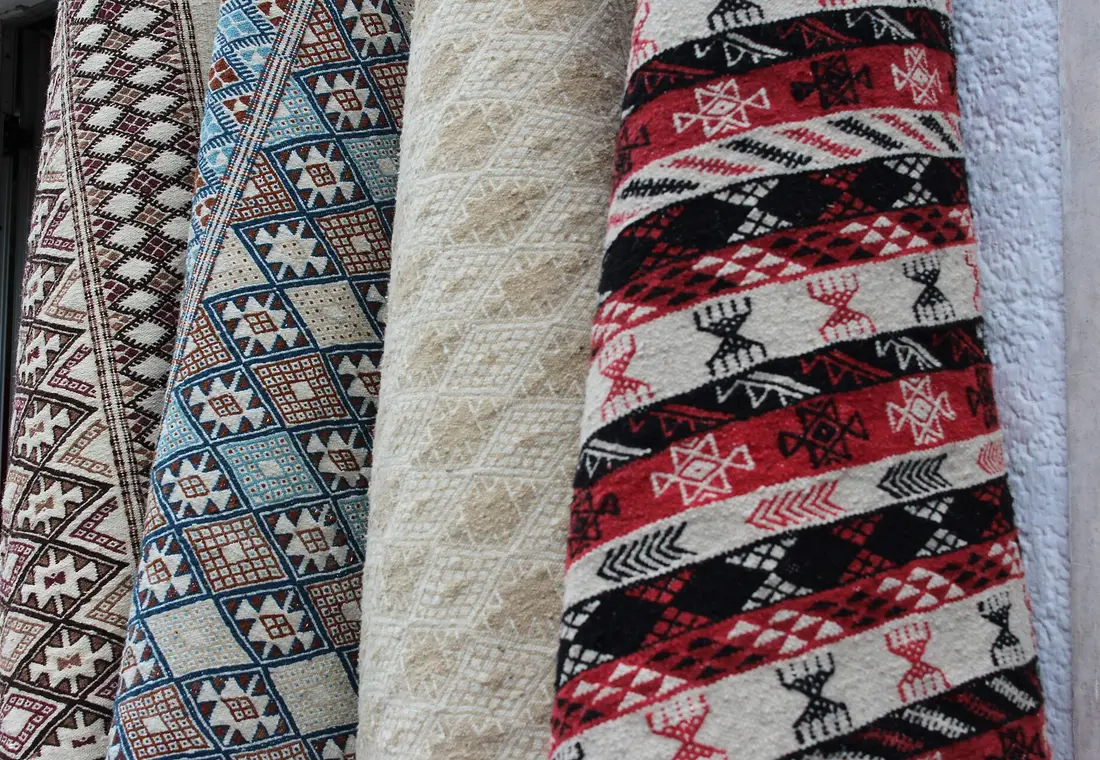 Tapis berbères roulés aux motifs traditionnels dans un souk marocain